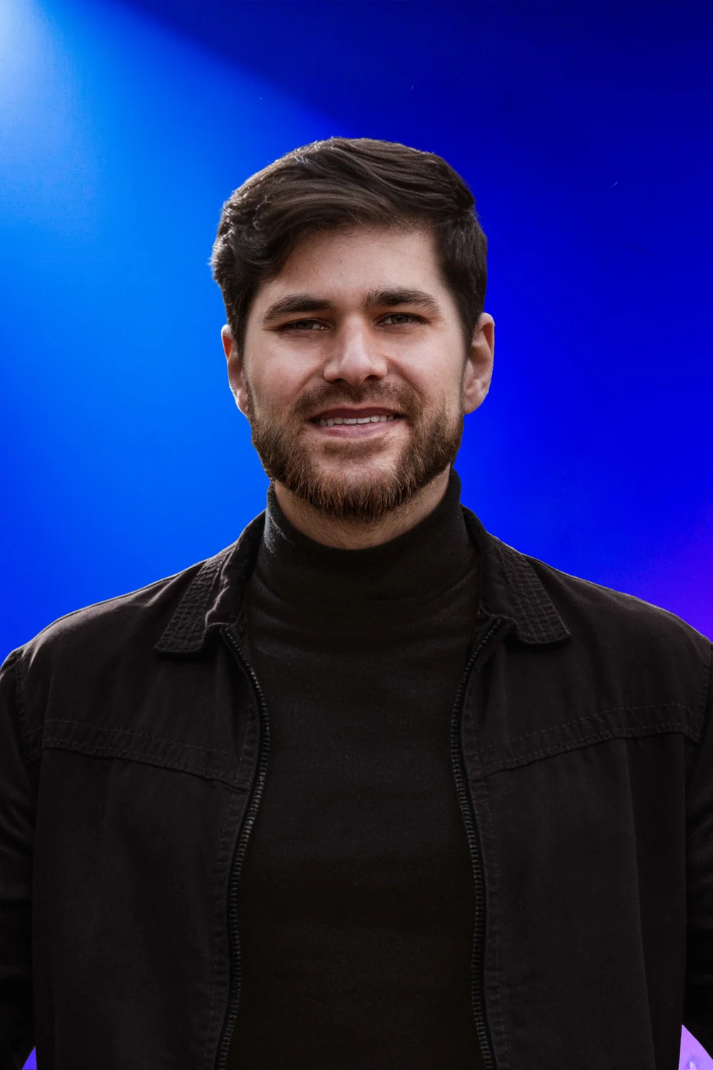 Iury F. Santos sorrindo, de frente, sob luz azul e violeta